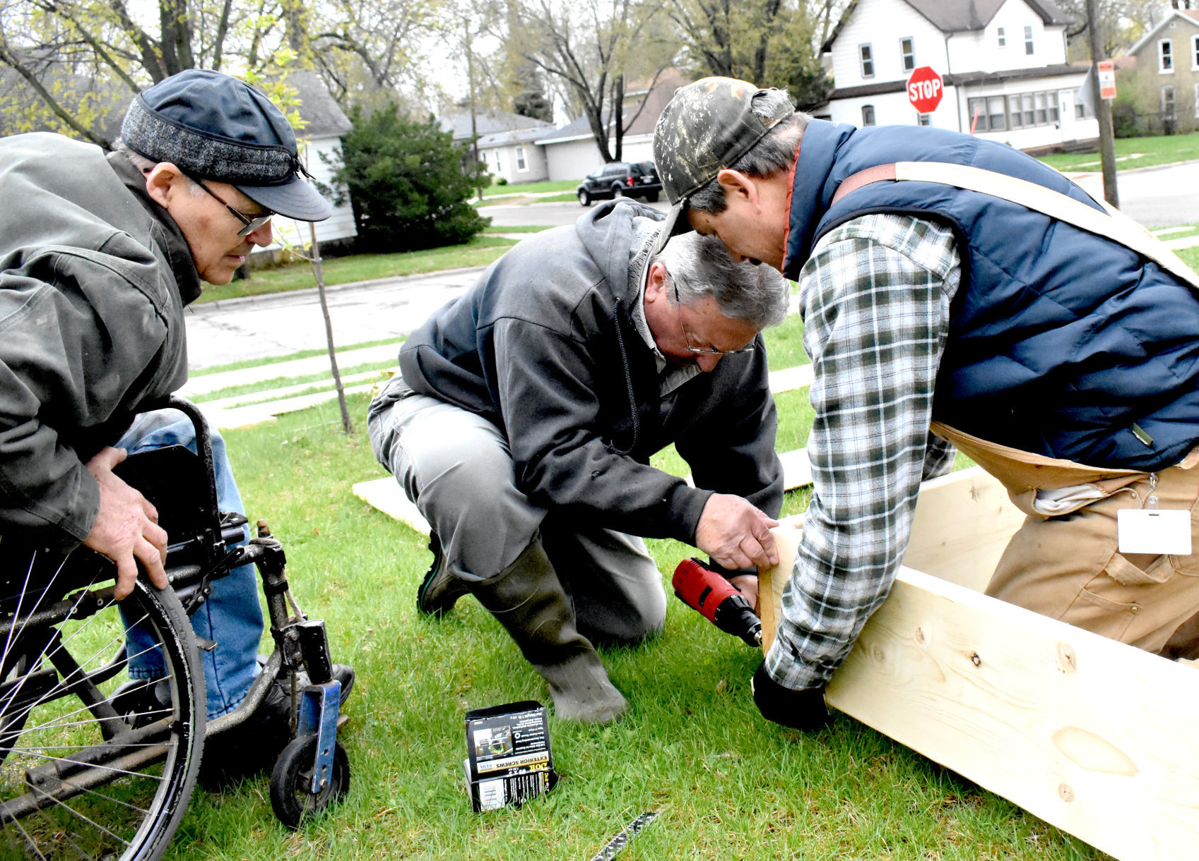 Gentlemen build raised garden bed together in Portage